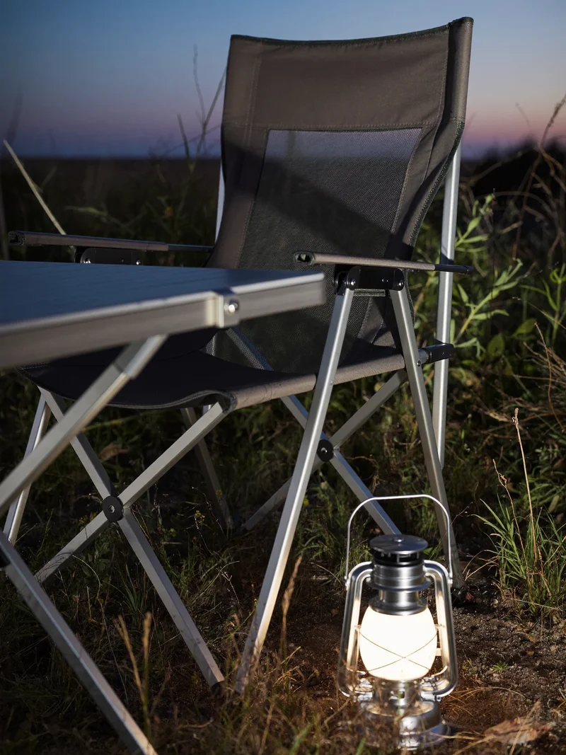 Klappstuhl und Falttisch mit leuchtender Laterne auf einem Campingplatz in der Dämmerung